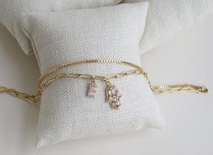 A Beautiful Combination of our Paper Clip and Box Chain, it’s two chains on a single clasp so it’s like a double layer in one.  This Anklet has a diamond hamsa and a petite diamond letters (A-Z). a beautiful Personalized Piece of Jewelry.